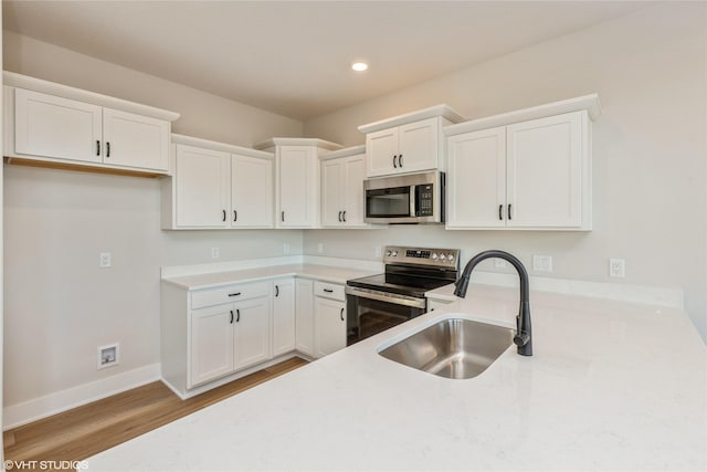 kitchen with hardwood / wood-style flooring, sink, white cabinetry, and stainless steel appliances