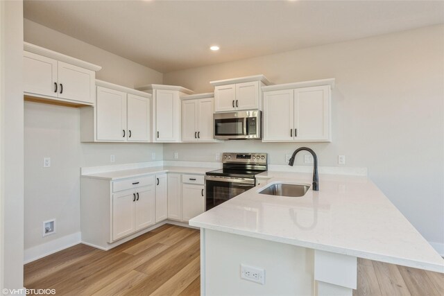 kitchen featuring kitchen peninsula, stainless steel appliances, white cabinets, and sink