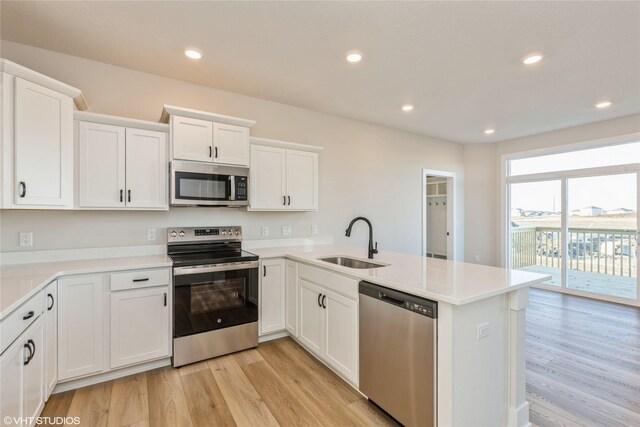 kitchen featuring kitchen peninsula, light wood-type flooring, stainless steel appliances, and sink