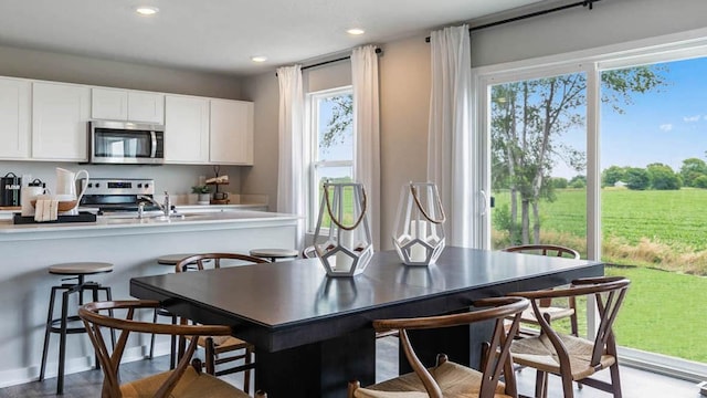 kitchen with appliances with stainless steel finishes, light countertops, white cabinetry, a sink, and recessed lighting