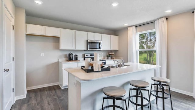 kitchen featuring dark wood-type flooring, white cabinetry, stainless steel appliances, and a sink