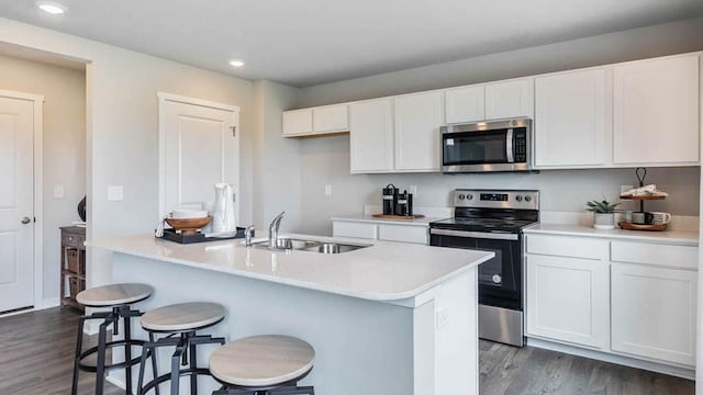 kitchen featuring white cabinets, dark wood-style floors, stainless steel appliances, light countertops, and a sink