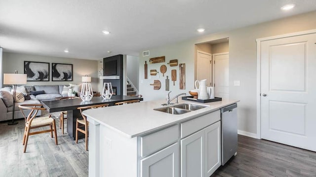 kitchen featuring recessed lighting, open floor plan, a sink, light wood-type flooring, and dishwasher