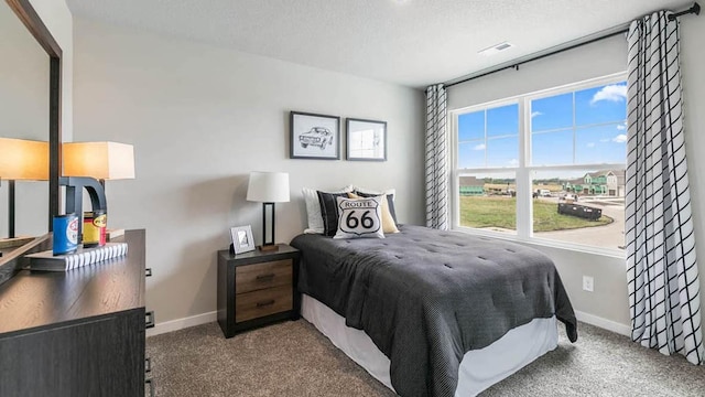 bedroom featuring a textured ceiling, carpet flooring, visible vents, and baseboards