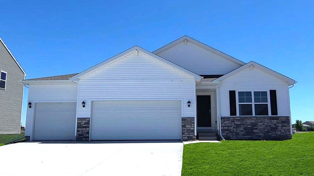 1040 Westridge St SW, Bondurant, IA 50035 - view of front of property with an attached garage, driveway, stone siding, and a front lawn