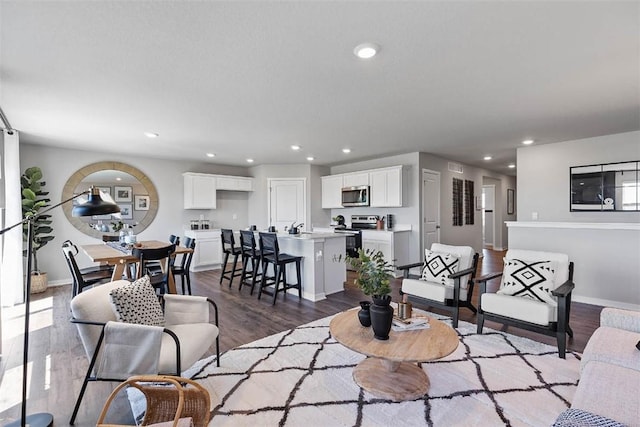 living area with baseboards, dark wood finished floors, and recessed lighting