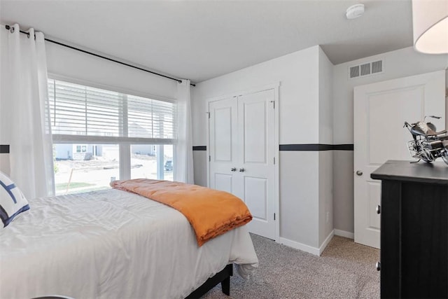 carpeted bedroom with a closet, visible vents, and baseboards