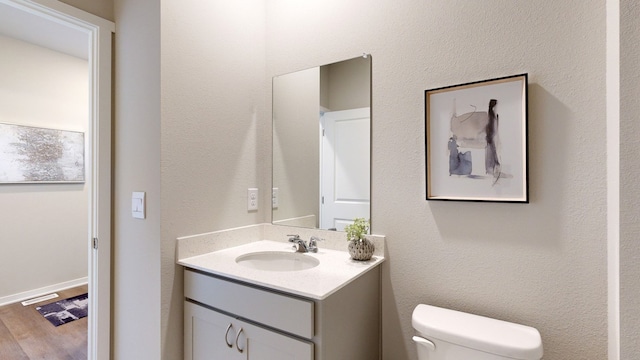 bathroom with toilet, hardwood / wood-style flooring, and vanity