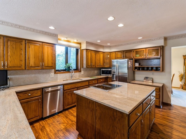 kitchen with stainless steel appliances, a center island, light stone countertops, sink, and decorative backsplash