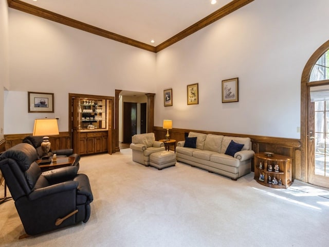 carpeted living room with crown molding, decorative columns, and a towering ceiling