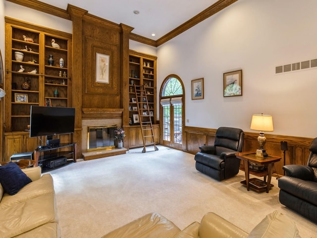 carpeted living room with a fireplace, crown molding, french doors, and built in features