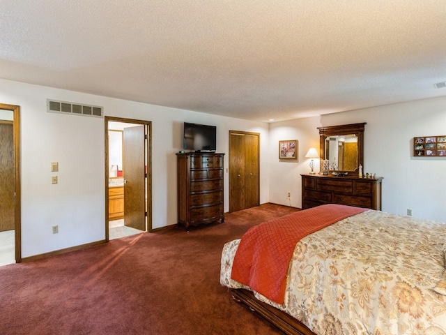 bedroom featuring a closet, connected bathroom, dark colored carpet, and a textured ceiling