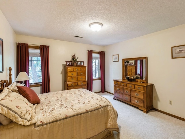 carpeted bedroom featuring multiple windows and a textured ceiling