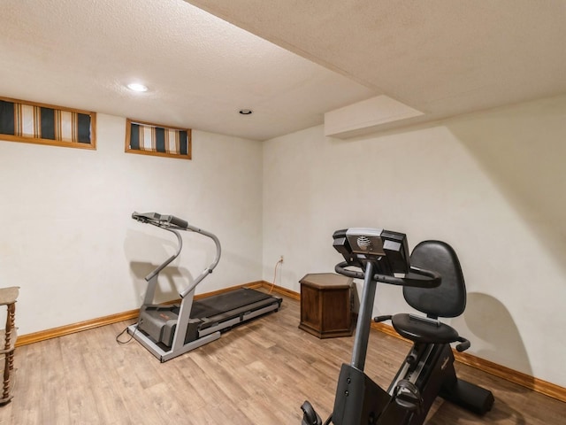 exercise room featuring light hardwood / wood-style flooring and a textured ceiling