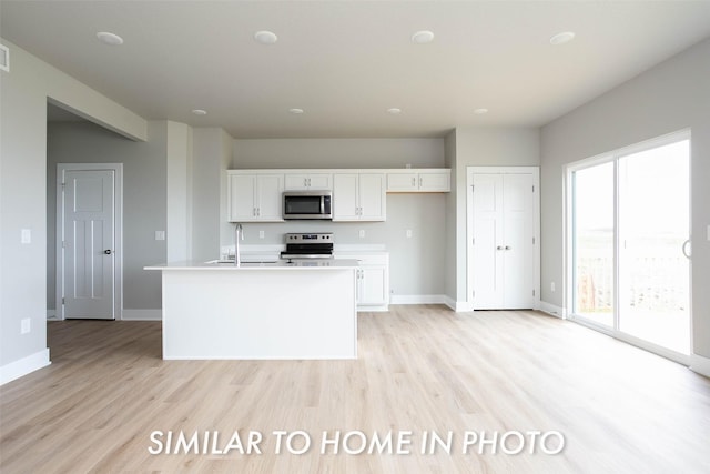 kitchen featuring baseboards, white cabinetry, stainless steel appliances, and light wood finished floors