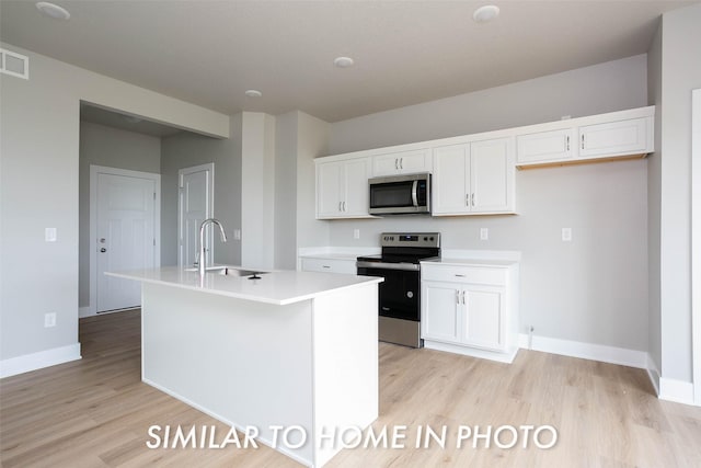 kitchen with white cabinets, stainless steel appliances, light wood-type flooring, and a sink