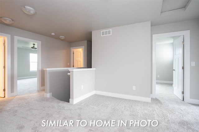 spare room featuring attic access, carpet floors, visible vents, and baseboards