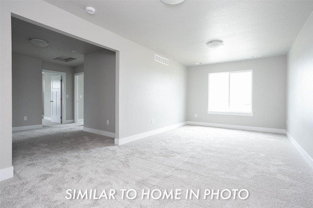 carpeted spare room featuring visible vents and baseboards