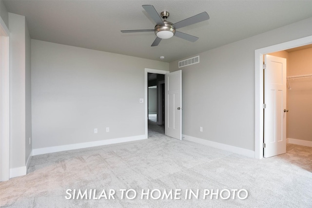 unfurnished bedroom featuring baseboards, a spacious closet, visible vents, carpet, and a ceiling fan