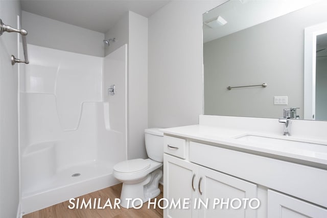bathroom featuring toilet, visible vents, wood finished floors, a shower, and vanity