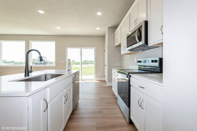 2304 Chan Dr, Adel, IA 50003 - kitchen with stainless steel appliances, recessed lighting, a textured ceiling, light countertops, and white cabinets