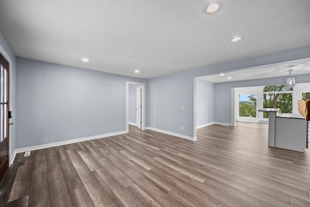 unfurnished living room with hardwood / wood-style flooring and a textured ceiling