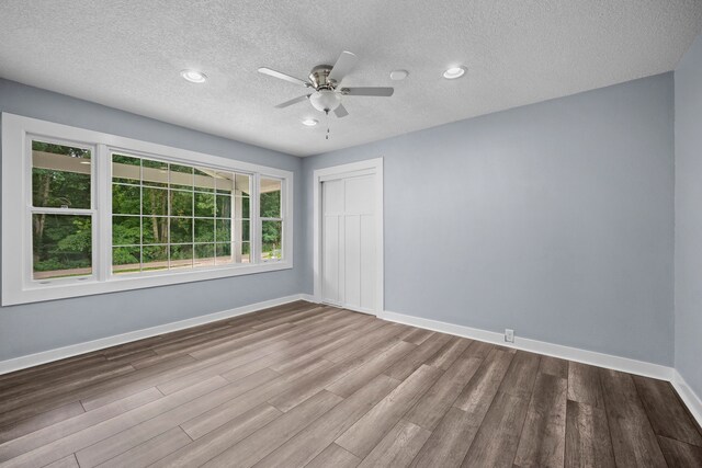 empty room with hardwood / wood-style flooring, a textured ceiling, and a healthy amount of sunlight