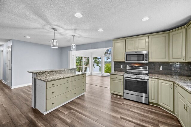 kitchen with pendant lighting, tasteful backsplash, wood-type flooring, gas range, and light stone countertops