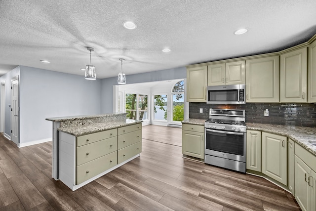 kitchen featuring light stone countertops, appliances with stainless steel finishes, decorative backsplash, and pendant lighting