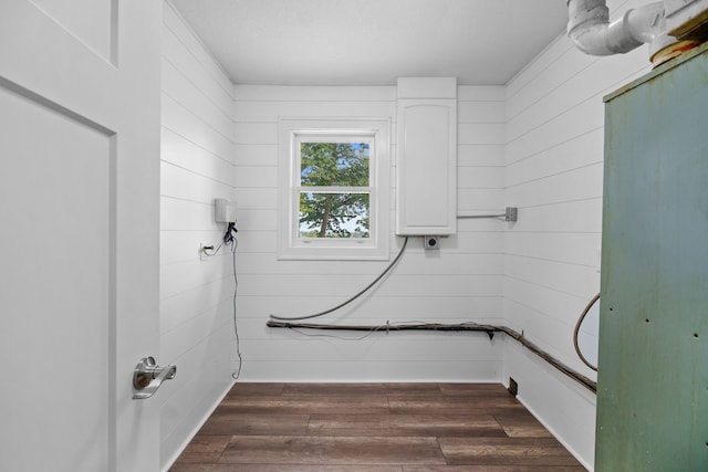 laundry area with wooden walls and dark wood-type flooring