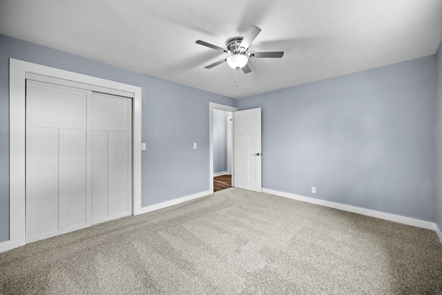 unfurnished bedroom with carpet, baseboards, ceiling fan, and a closet