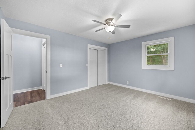 unfurnished bedroom featuring ceiling fan, a closet, and dark carpet