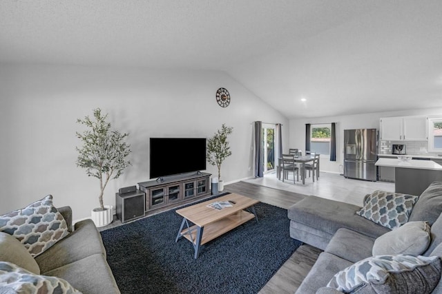 living room featuring vaulted ceiling, light wood-style flooring, and baseboards