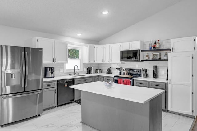 kitchen featuring appliances with stainless steel finishes, lofted ceiling, marble finish floor, and a sink