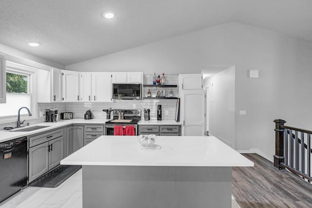 kitchen featuring vaulted ceiling, appliances with stainless steel finishes, backsplash, and a sink