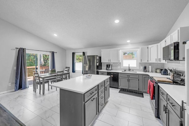 kitchen with marble finish floor, appliances with stainless steel finishes, vaulted ceiling, and backsplash