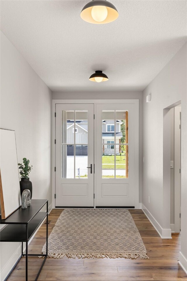 doorway with a textured ceiling and hardwood / wood-style flooring