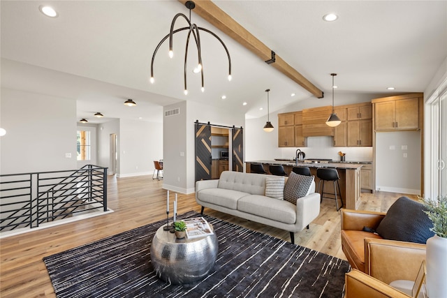 living area featuring vaulted ceiling with beams, a barn door, visible vents, baseboards, and light wood-style floors