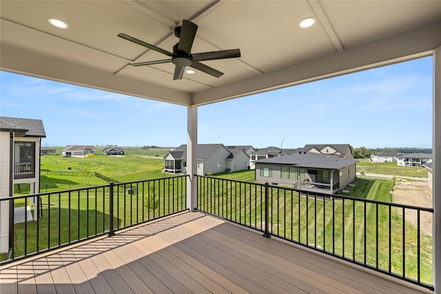 deck featuring a ceiling fan, a residential view, and a lawn