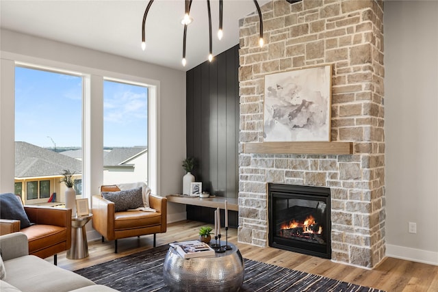 living room featuring baseboards, wood finished floors, and a stone fireplace