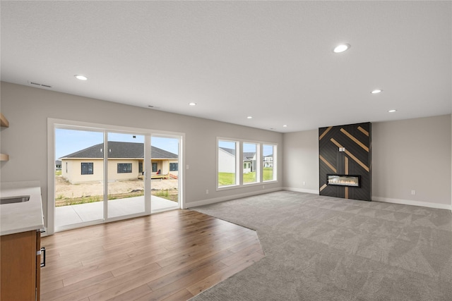 unfurnished living room with visible vents, baseboards, light wood-style flooring, a fireplace, and recessed lighting