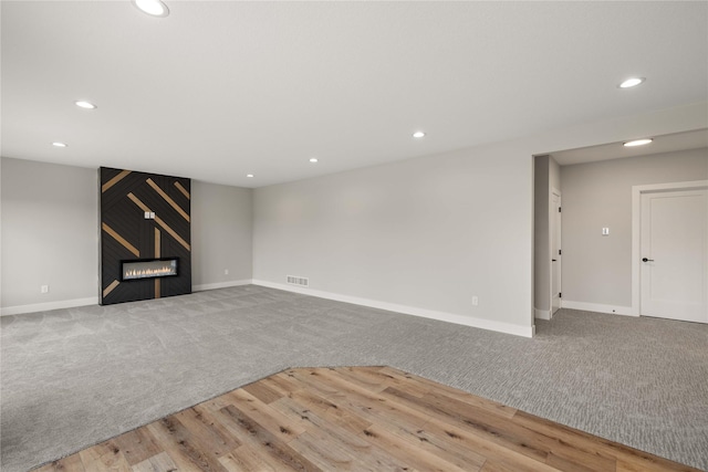 interior space with visible vents, baseboards, wood finished floors, a fireplace, and recessed lighting