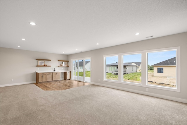 unfurnished living room with recessed lighting, light colored carpet, visible vents, and baseboards