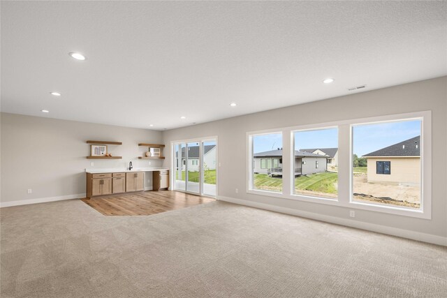 1185 NW 28th St, Grimes, IA 50111 - unfurnished living room with light carpet, baseboards, recessed lighting, and bar
