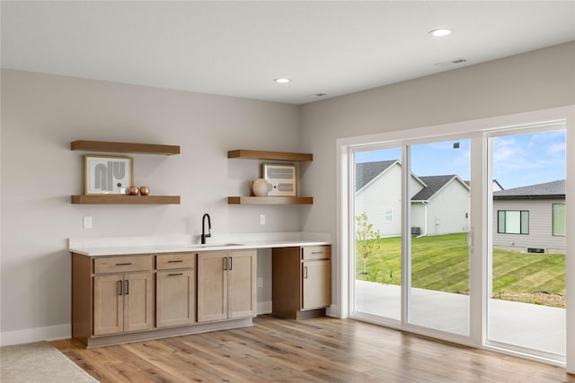 bar featuring light wood-style floors, recessed lighting, a sink, and baseboards