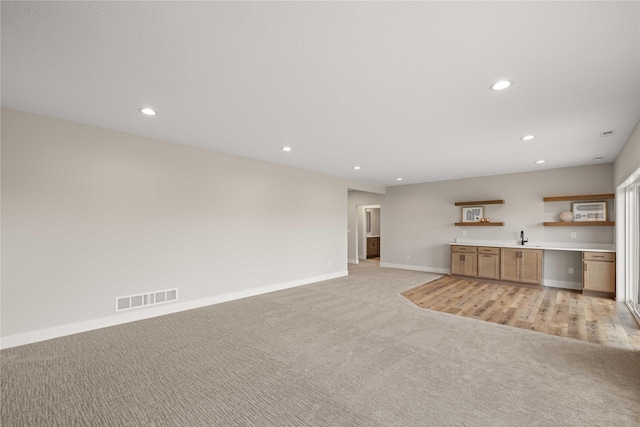 unfurnished living room featuring recessed lighting, visible vents, light carpet, and baseboards