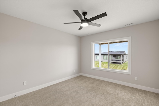 empty room featuring light carpet, a ceiling fan, visible vents, and baseboards