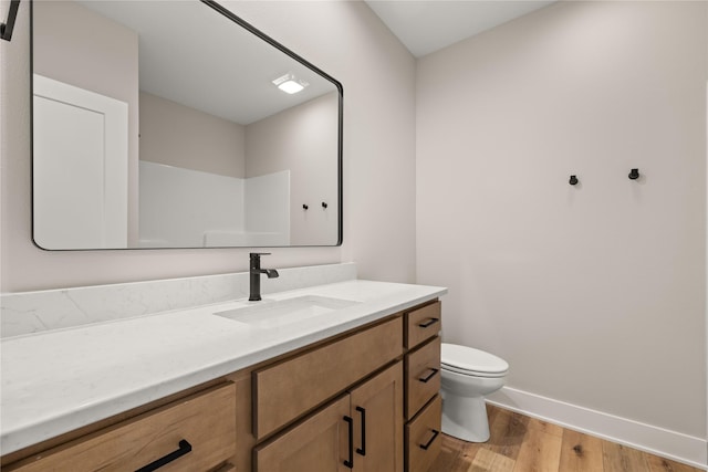 bathroom featuring baseboards, vanity, toilet, and wood finished floors