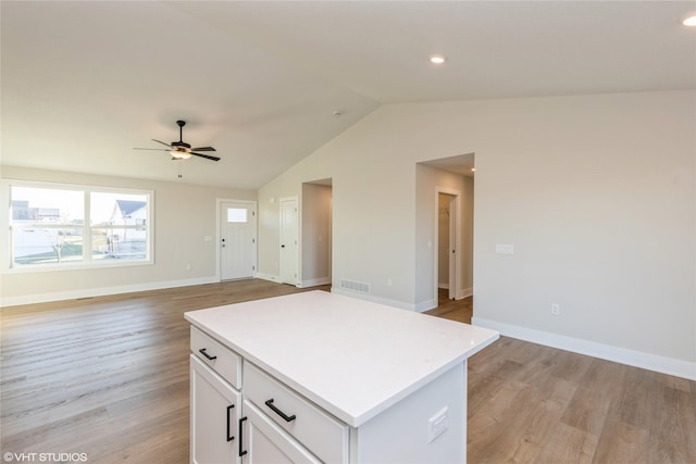 kitchen featuring white cabinets, lofted ceiling, light hardwood / wood-style flooring, and a kitchen island