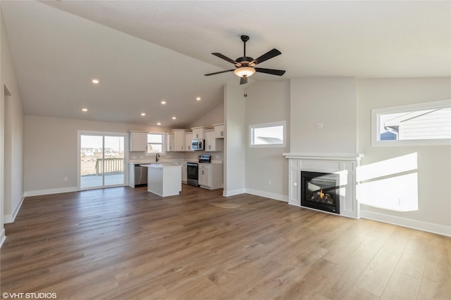 unfurnished living room with ceiling fan, light hardwood / wood-style floors, and lofted ceiling